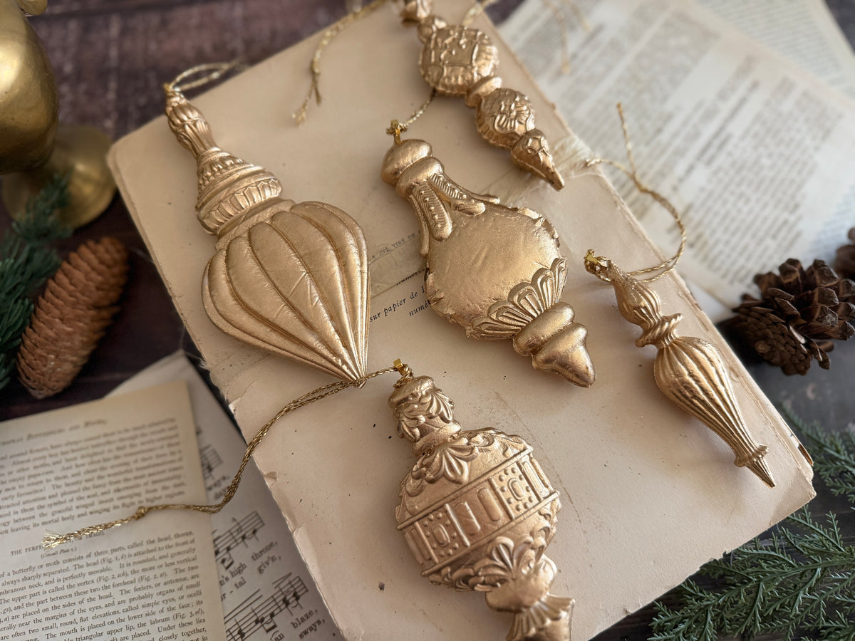 Six Baubles Mould ornaments by I.O.D. (2026 Limited Release) arranged among pine cones and greenery.