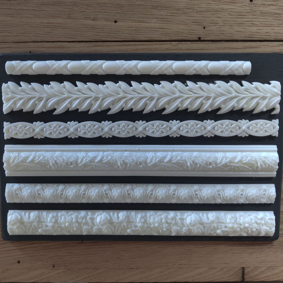 Six white Notions Amazing Casting Resin trim borders arranged on a plain black background.