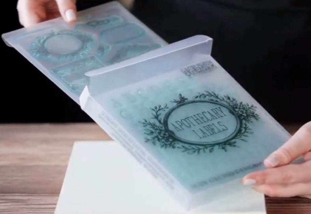 Clear sheet labeled Apothecary Mini-Stamp by I.O.D. with decorative Iron Orchid Designs, held in hand.