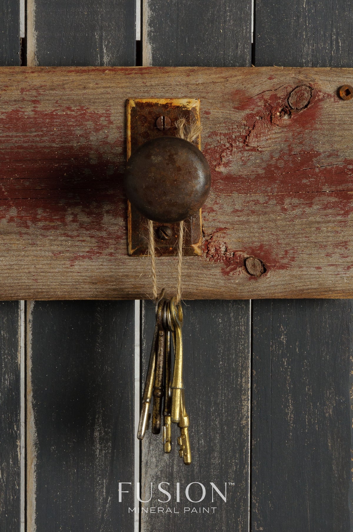 Rusty doorknob and old keys on wood, with Fusion Mineral Paint in Ash (dark charcoal grey) visible underneath.