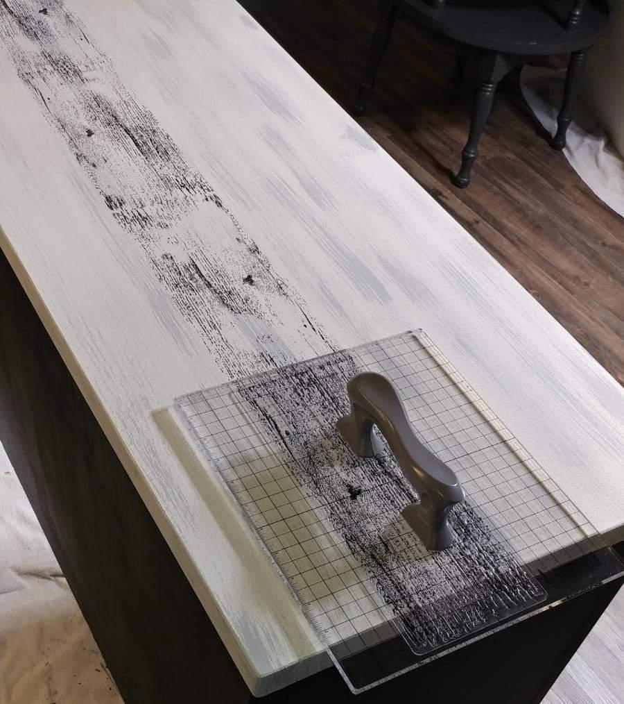 Barnwood Planks Stamp by IOD, creates a distressed black pattern on a white surface.