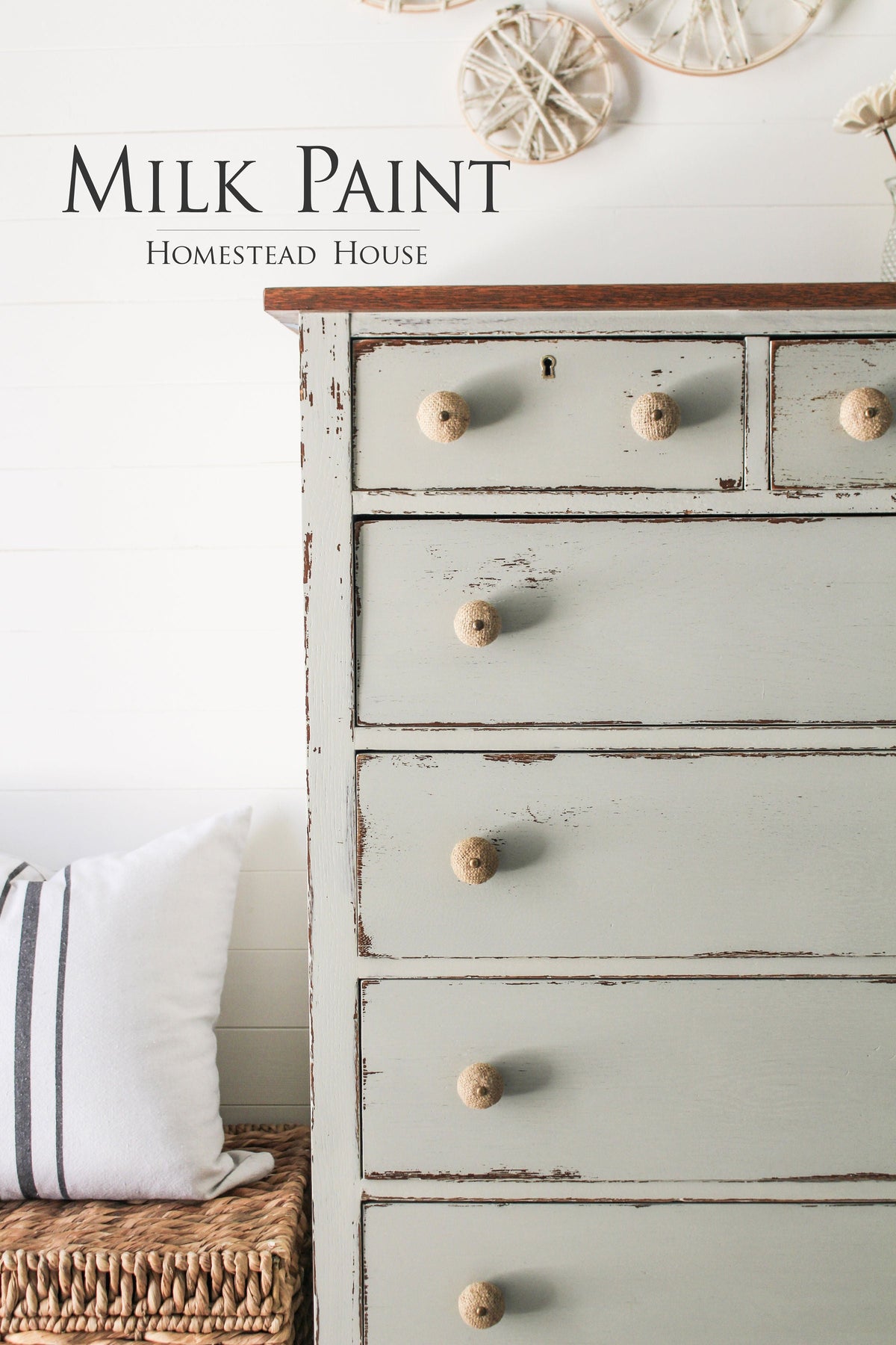 Light green Bedford Milk Paint dresser by Homestead House with wooden knobs, sitting above a wicker bench pillow.