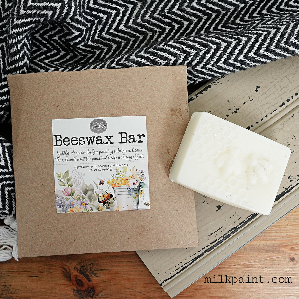 Old Fashioned Milk Paint Beeswax Bar with box on wood surface, next to a chevron cloth.
