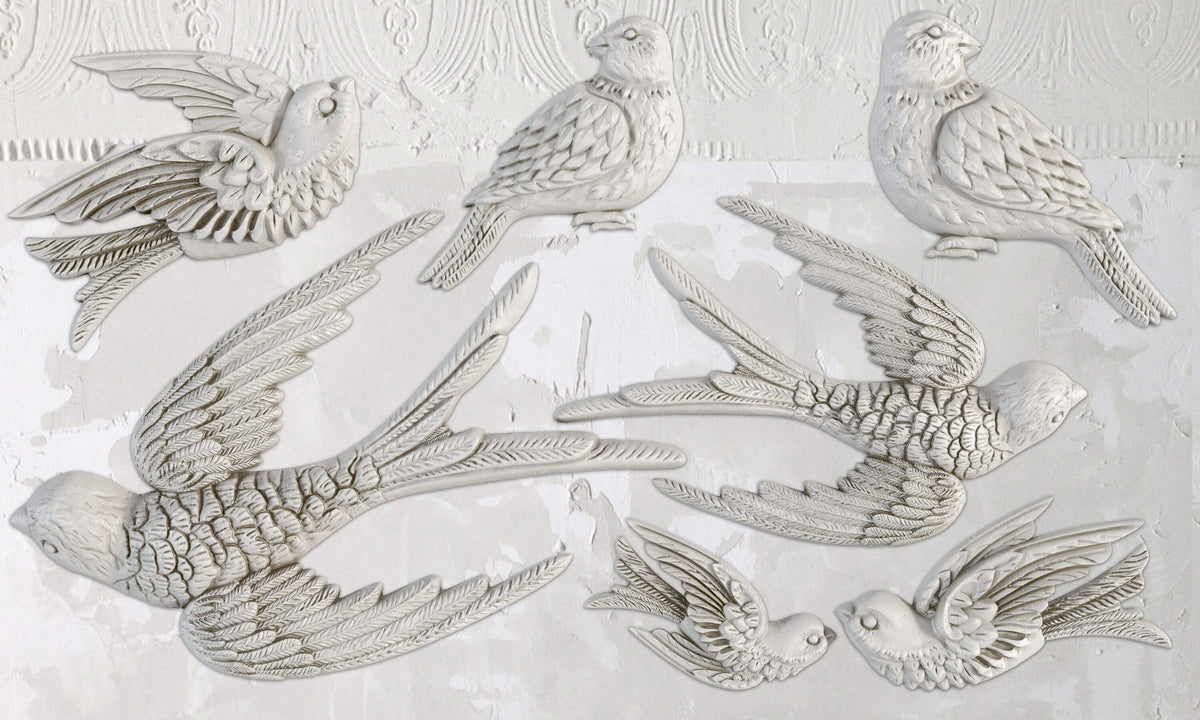Eight white birds made with Birdsong Mould by I.O.D. arranged on a textured white wall.