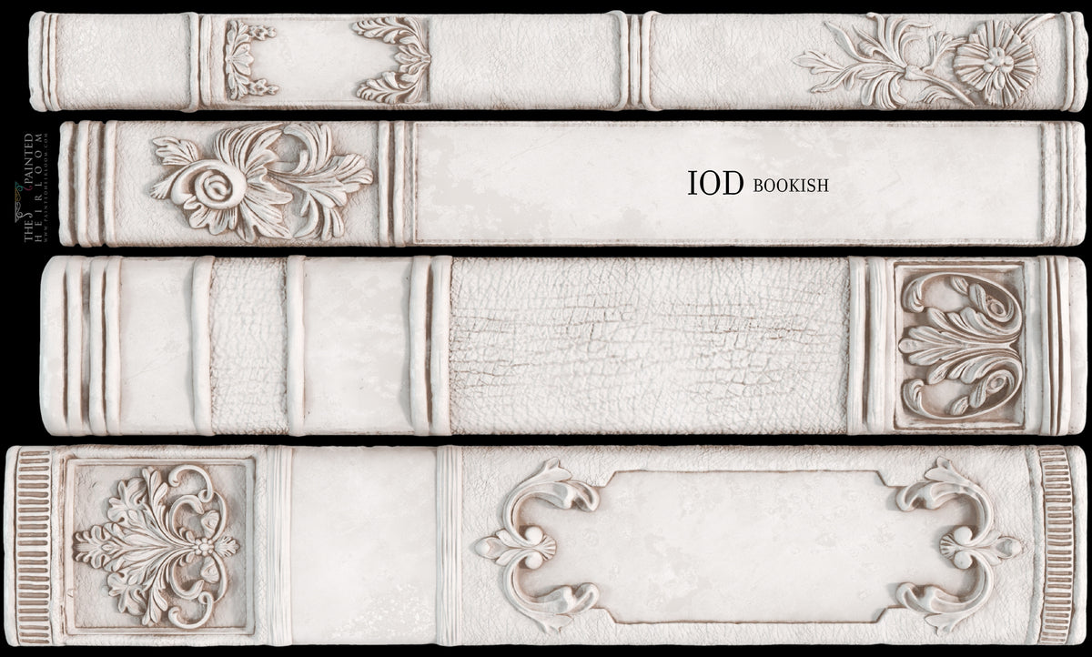 Four white book spines with ornate patterns made using the Bookish Mould by I.O.D. for faux decor displays.