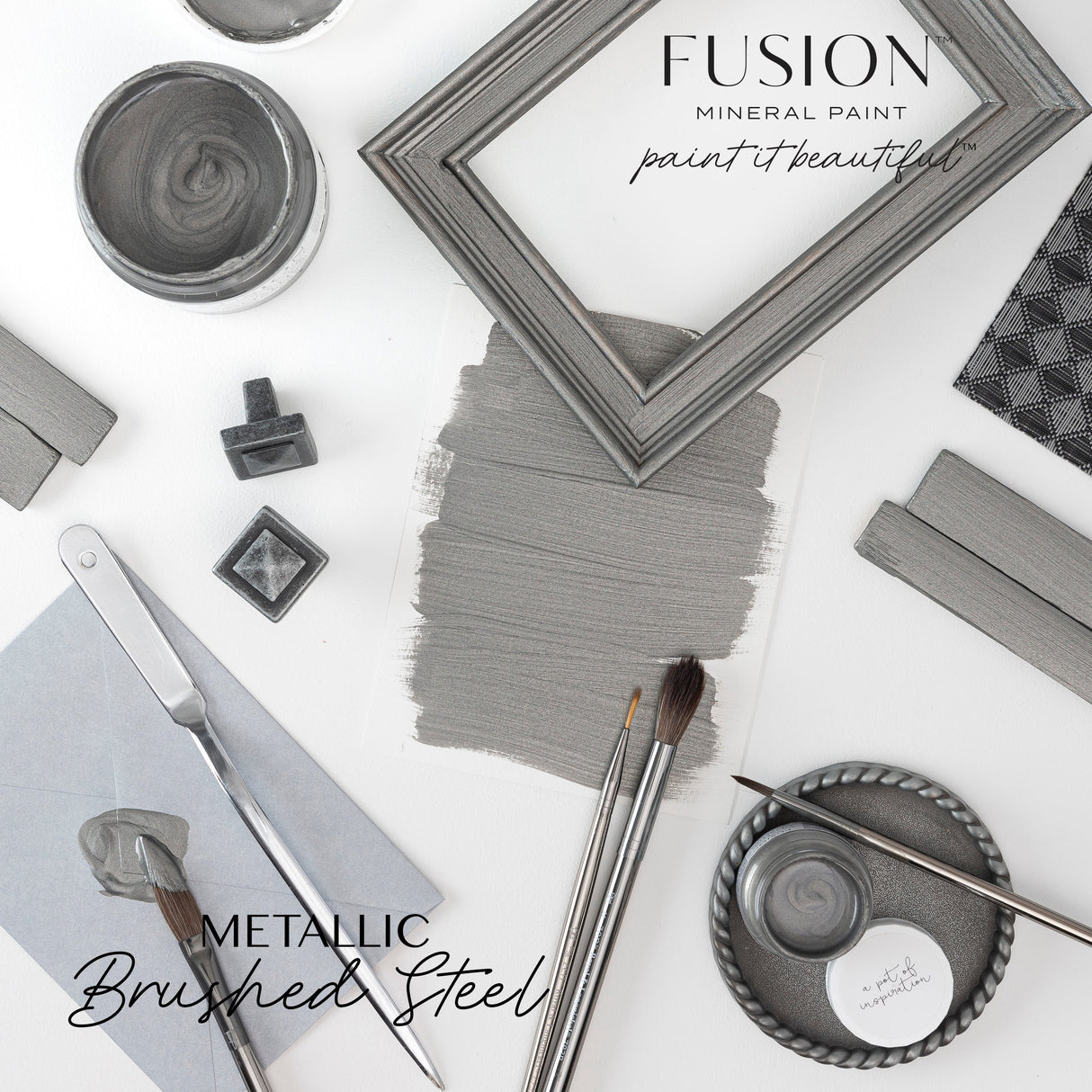Fusion Mineral Paint brushes, swatch, frames, and Brushed Steel Metallic paint cans arranged on a white surface.