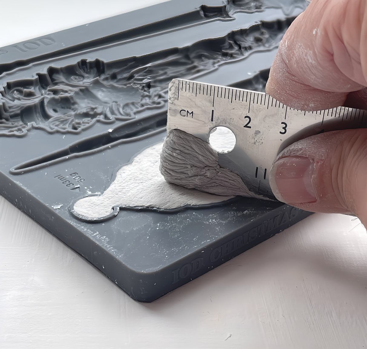Hand lifts clay from I.O.D. 2024 Limited Christmas Tapers Mould with Nordic patterns.