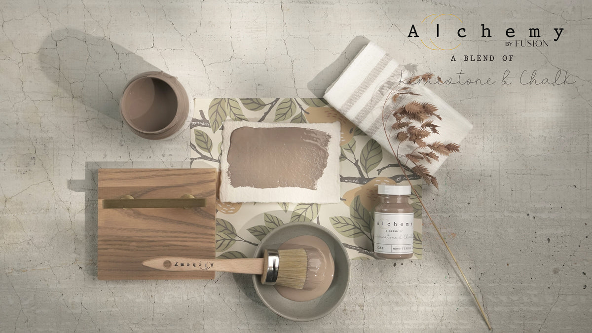 Alchemy by Fusion Mineral Paint, brush with wooden handle, jar, and color brochure on cracked surface.