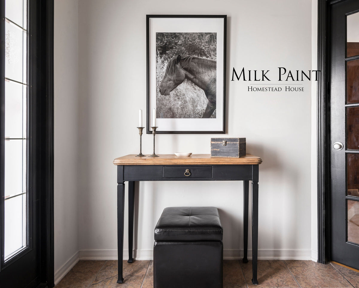 Desk painted in Coal Black Milk Paint by Homestead House with wood top; brand name visible on wall behind.