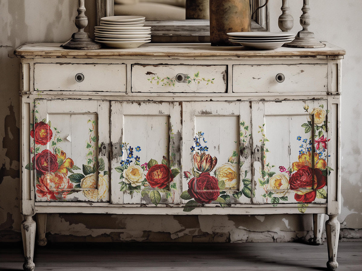 White cottage cabinet with I.O.D. Collage De Fleurs floral transfers, three drawers, and stacked dishes on top.