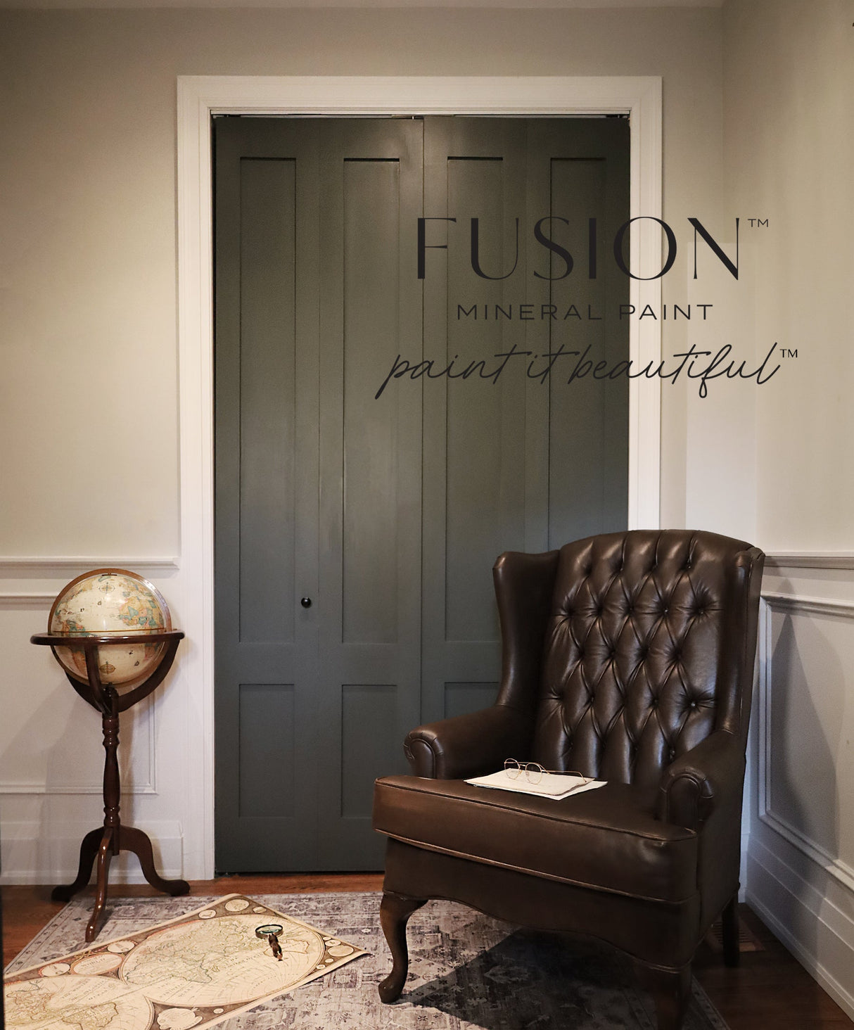 Brown leather armchair and globe beside doors painted in Everett by Fusion Mineral Paint; branding on wall.