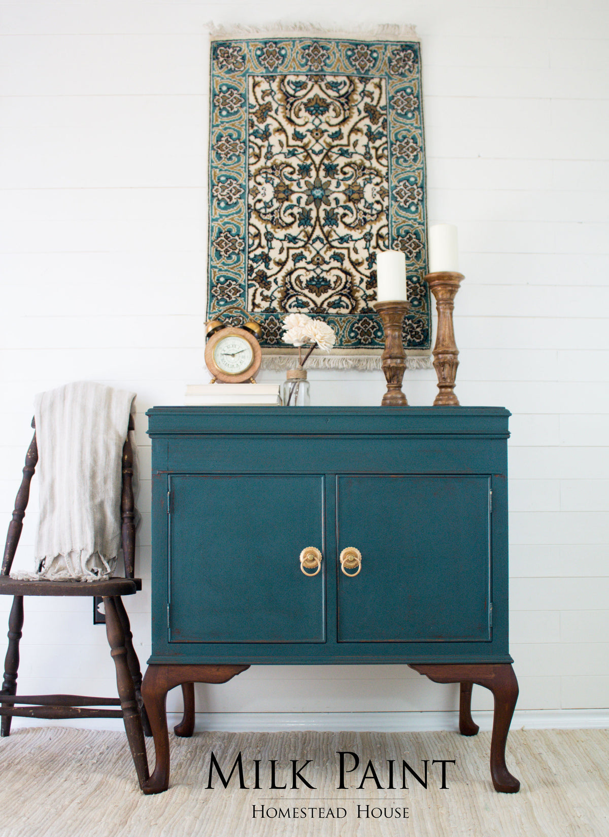 Teal Homestead House Gaspe Green Milk Paint cabinet with brass handles beside a wooden chair and draped cloth.
