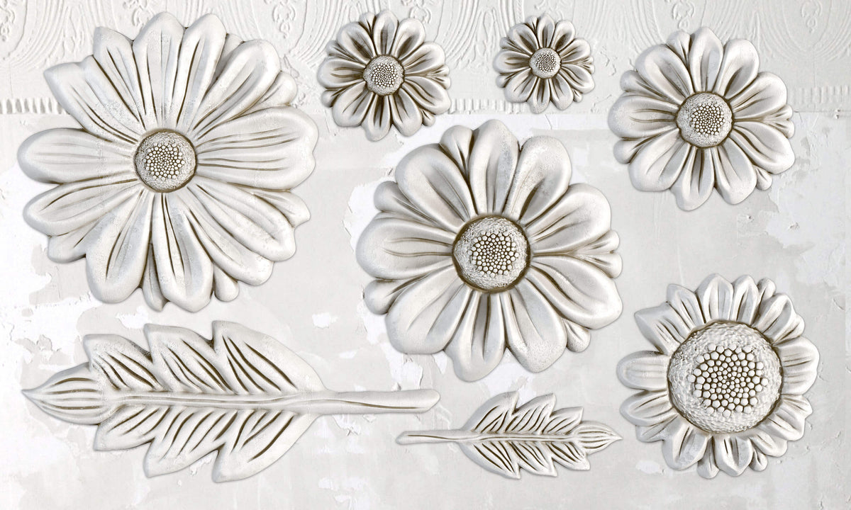 Eight white florals from the He Loves Me Mould by I.O.D. arranged on a textured, ornate wall.