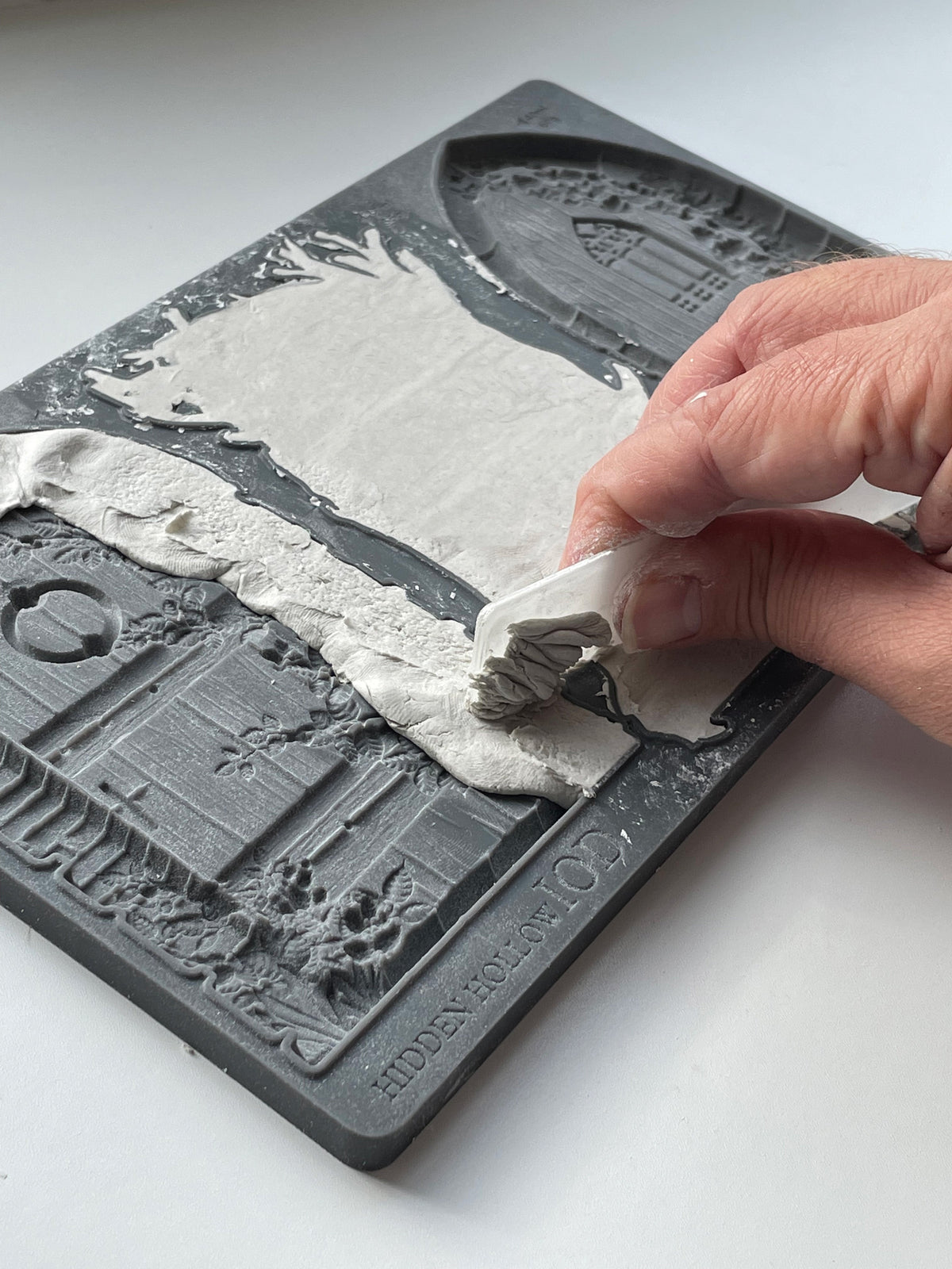 Hand lifting IOD Air Dry Clay from Hidden Hollow Mould with detailed doors and windows.