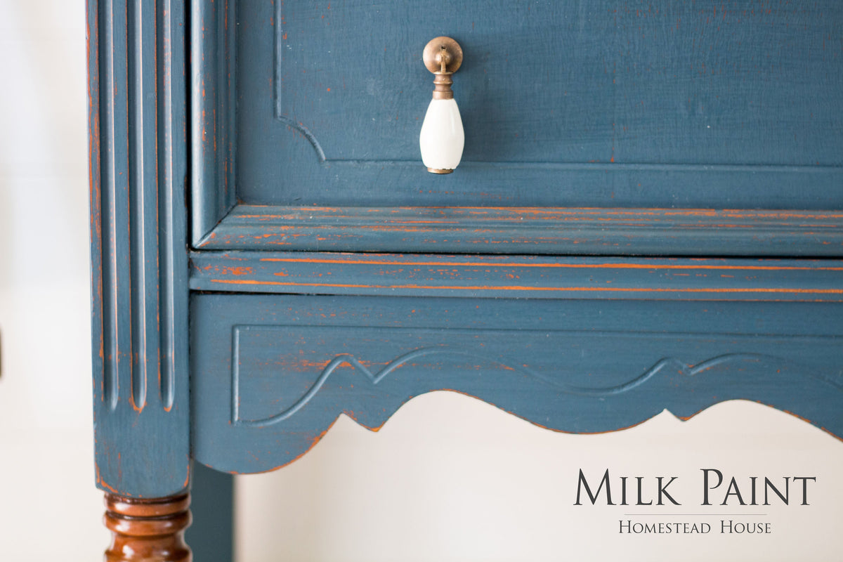 Blue wood cabinet in Homestead Blue Milk Paint by Homestead House with a white knob and visible brand text.