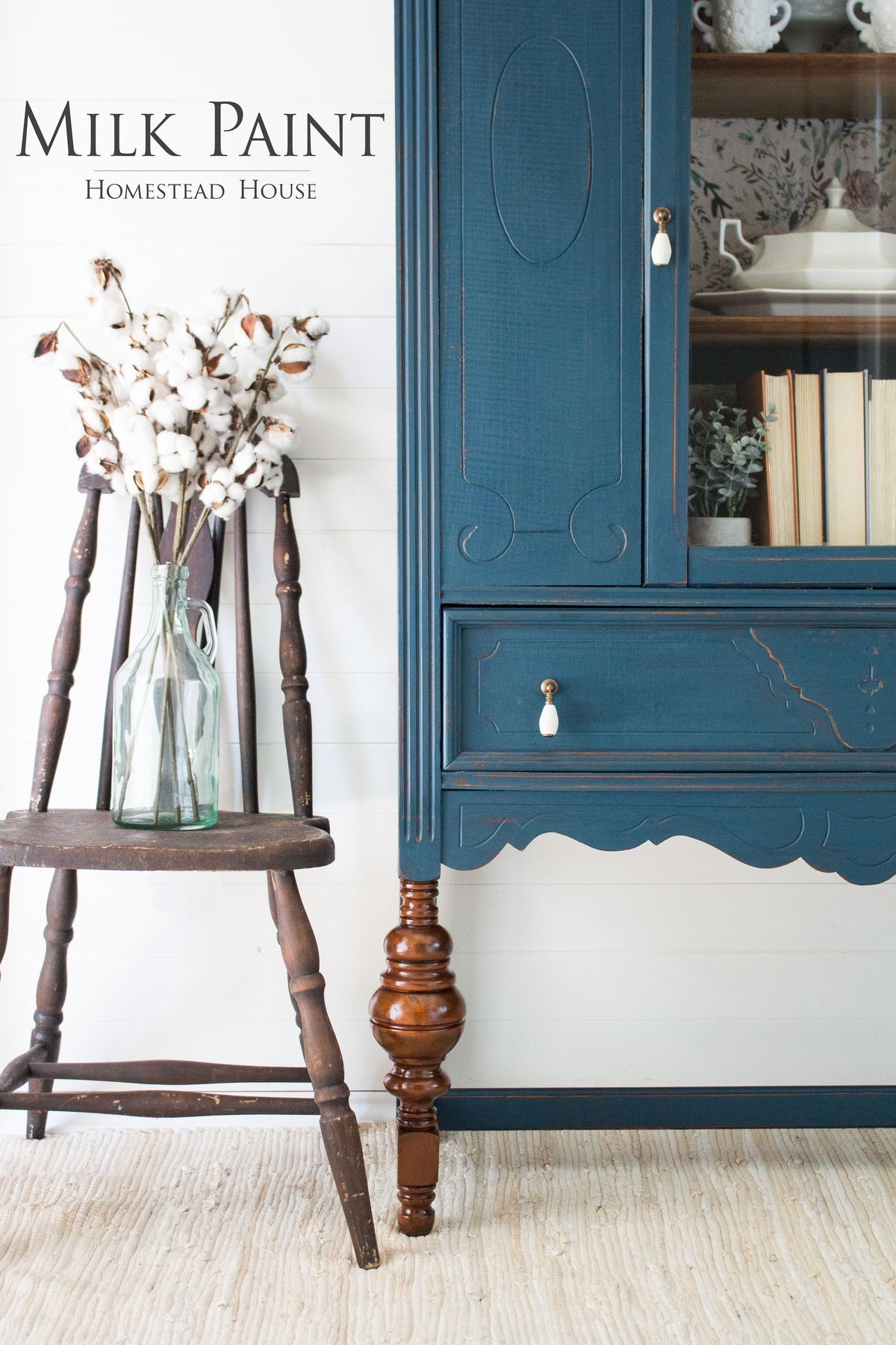 Wooden chair beside blue cabinet in Homestead Blue Milk Paint by Homestead House, with cotton stems on light rug.