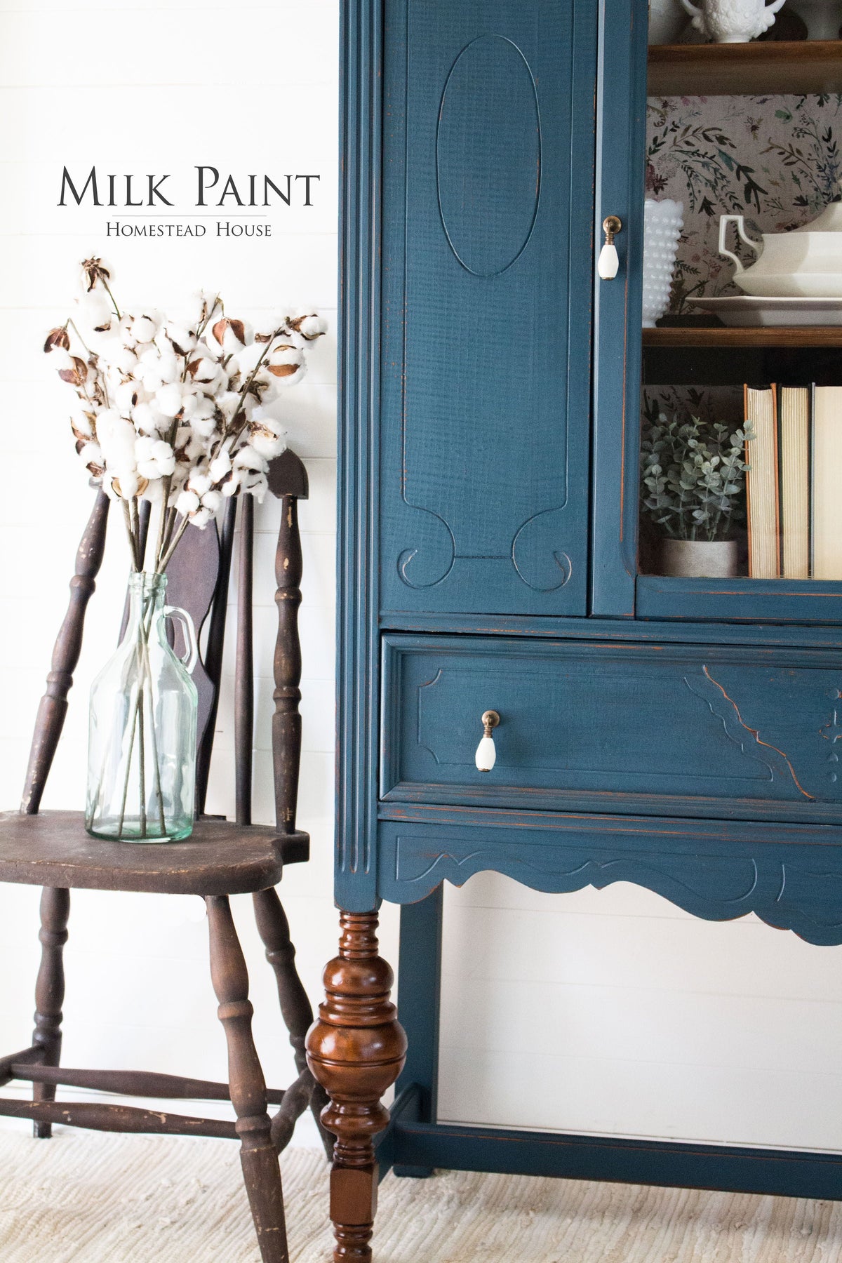 Wooden chair with cotton stems beside a Homestead House blue hutch labeled āMilk Paintā in Homestead Blue.