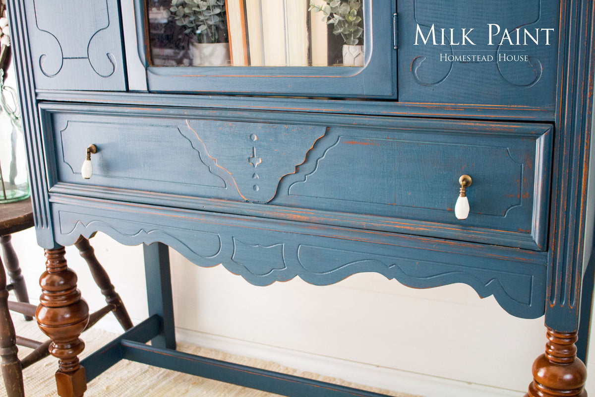 Homestead Blue Milk Paint wood cabinet by Homestead House with ornate details and white knobs, brand text visible.