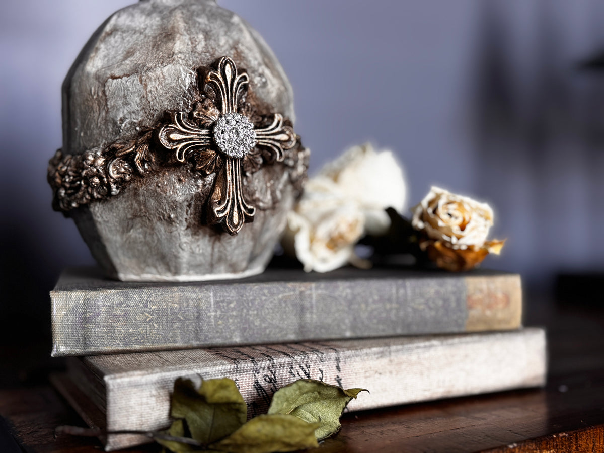 Stone with cross detail made using Les Croix Mould by I.O.D., displayed on stacked books, dried roses beside.
