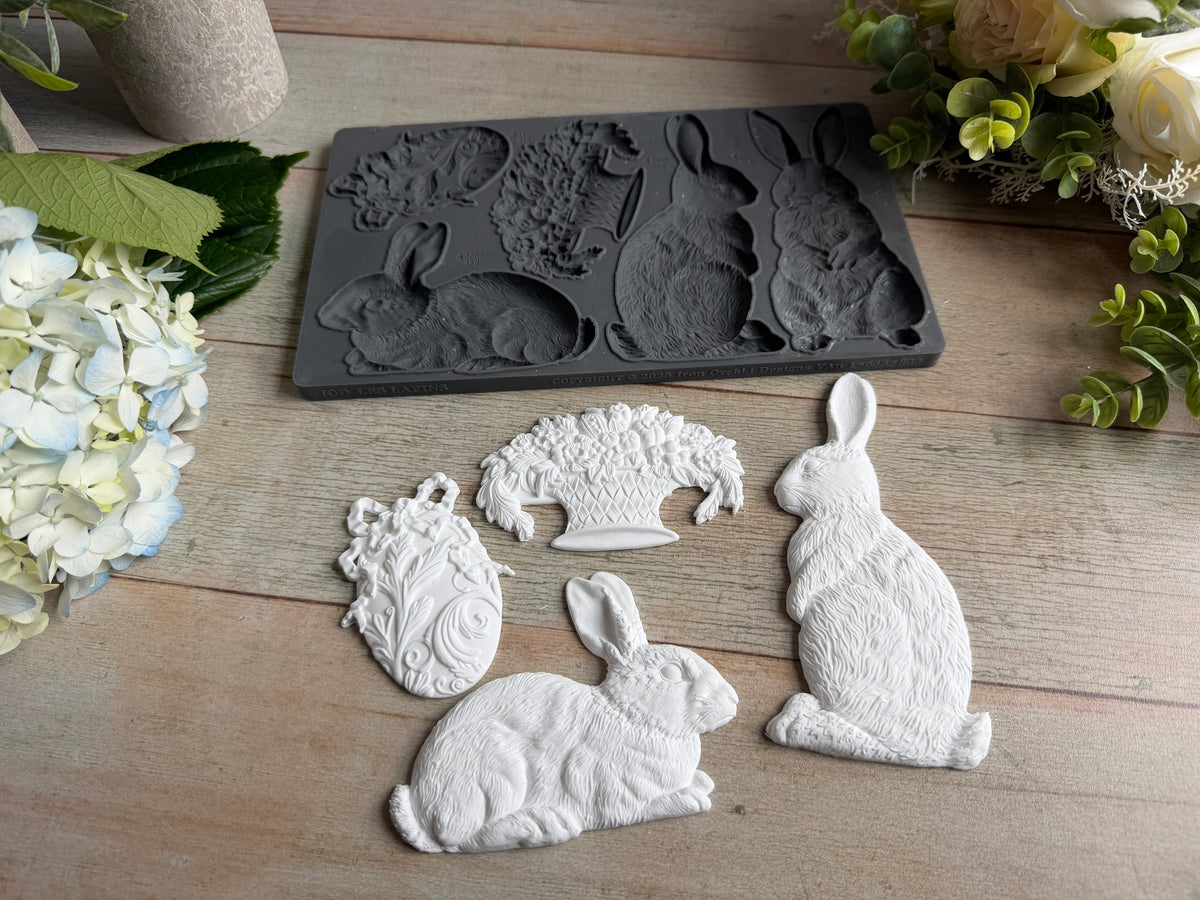 Les Lapins Mould by IOD with three white rabbit castings on wood, styled with faux flowers. Brand: I.O.D.