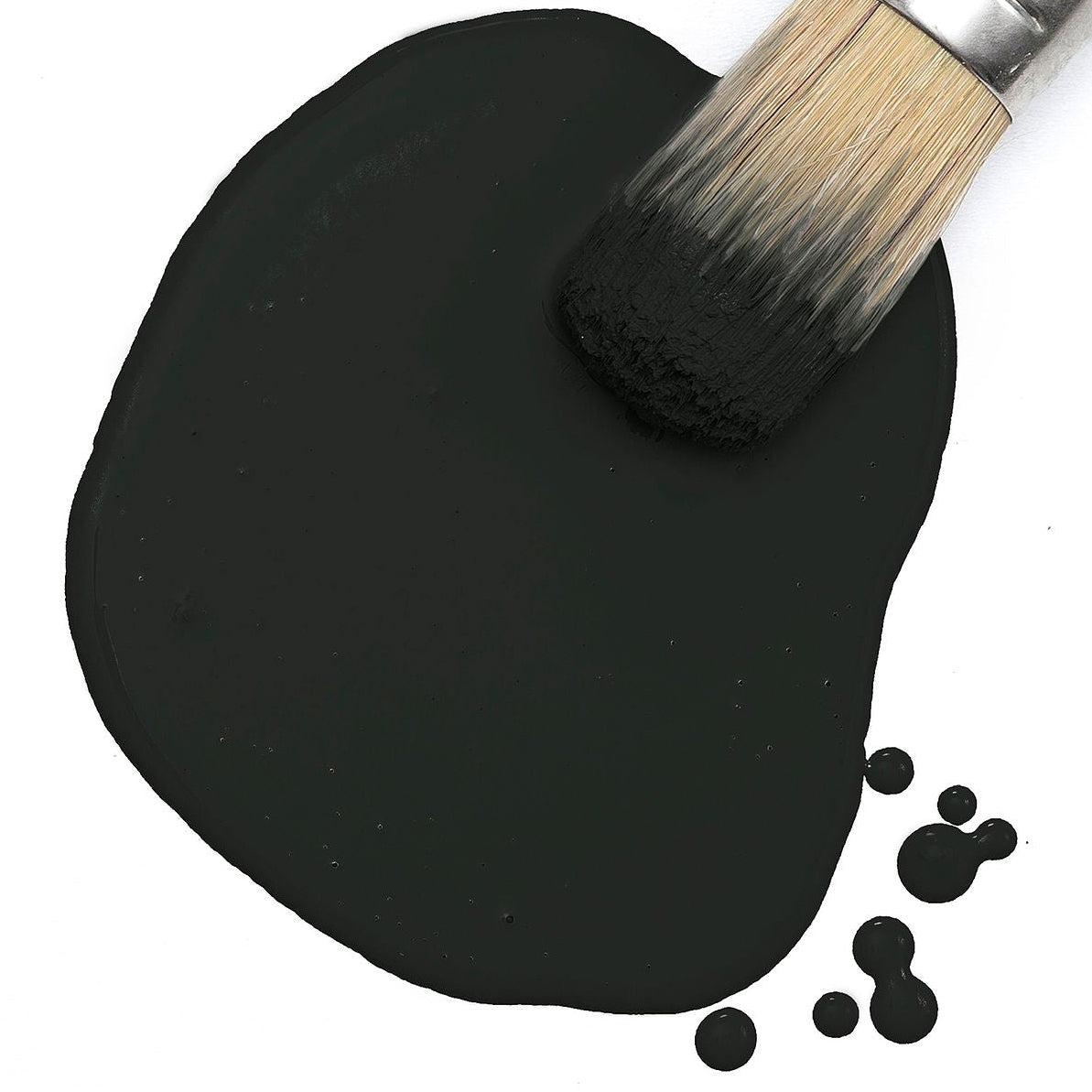 Paintbrush on spilled Fusion Mineral Paint Little Black Dress Milk Paint with droplets on white background.