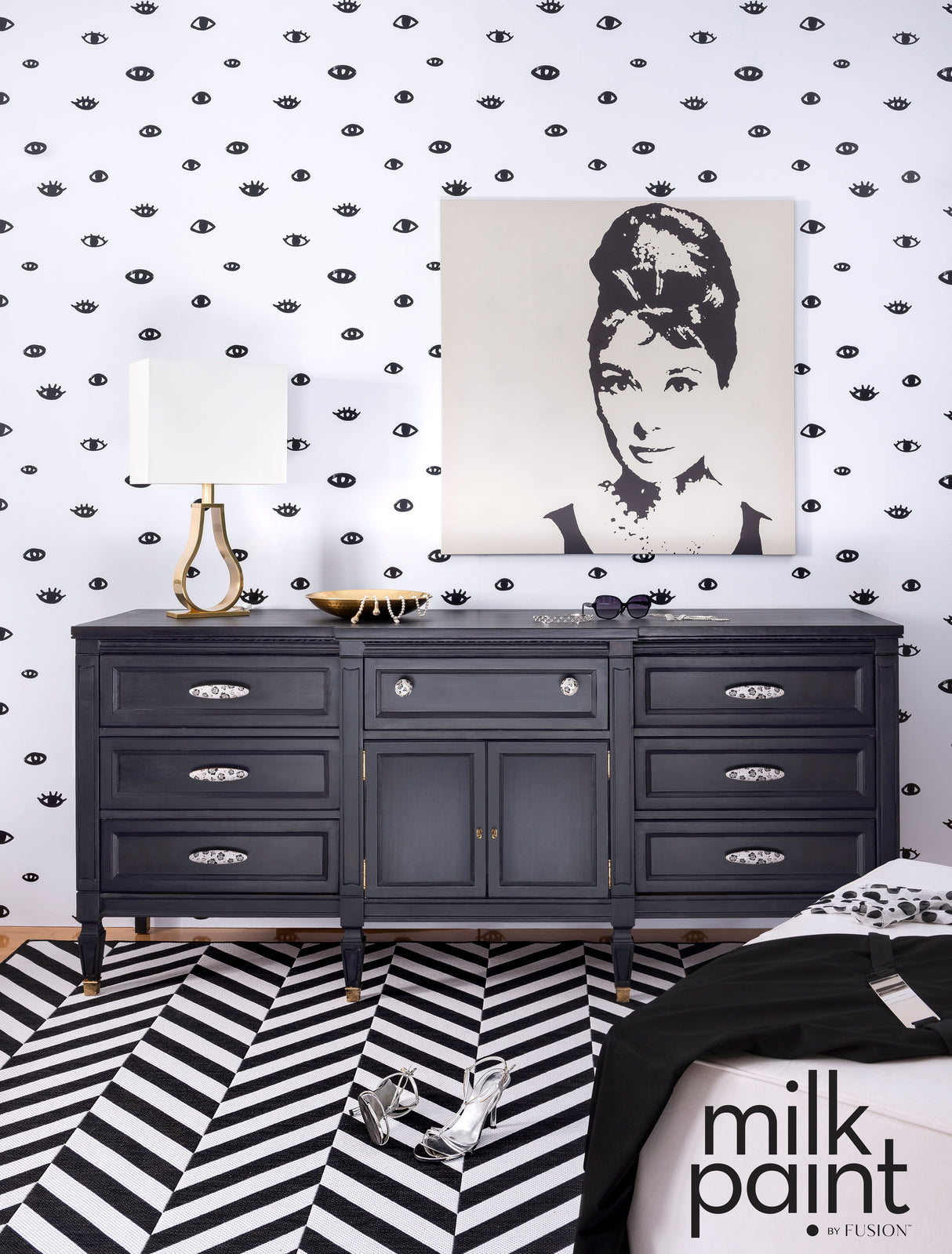 Dresser painted in Fusion Mineral Paint’s Little Black Dress beside lamp, set against polka dot eye-patterned wall.