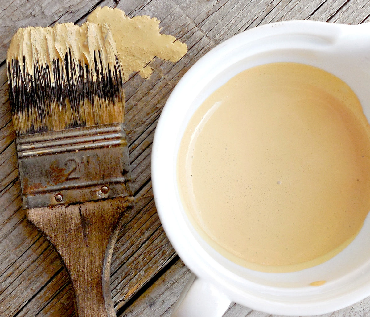 Brush with Love Bug by Old Fashioned Milk Paint next to a cup of matching beige paint on wood surface.