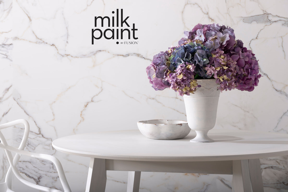 White round table with a vase, bowl, and Fusion Mineral Paint Marble Milk Paint packaging visible.