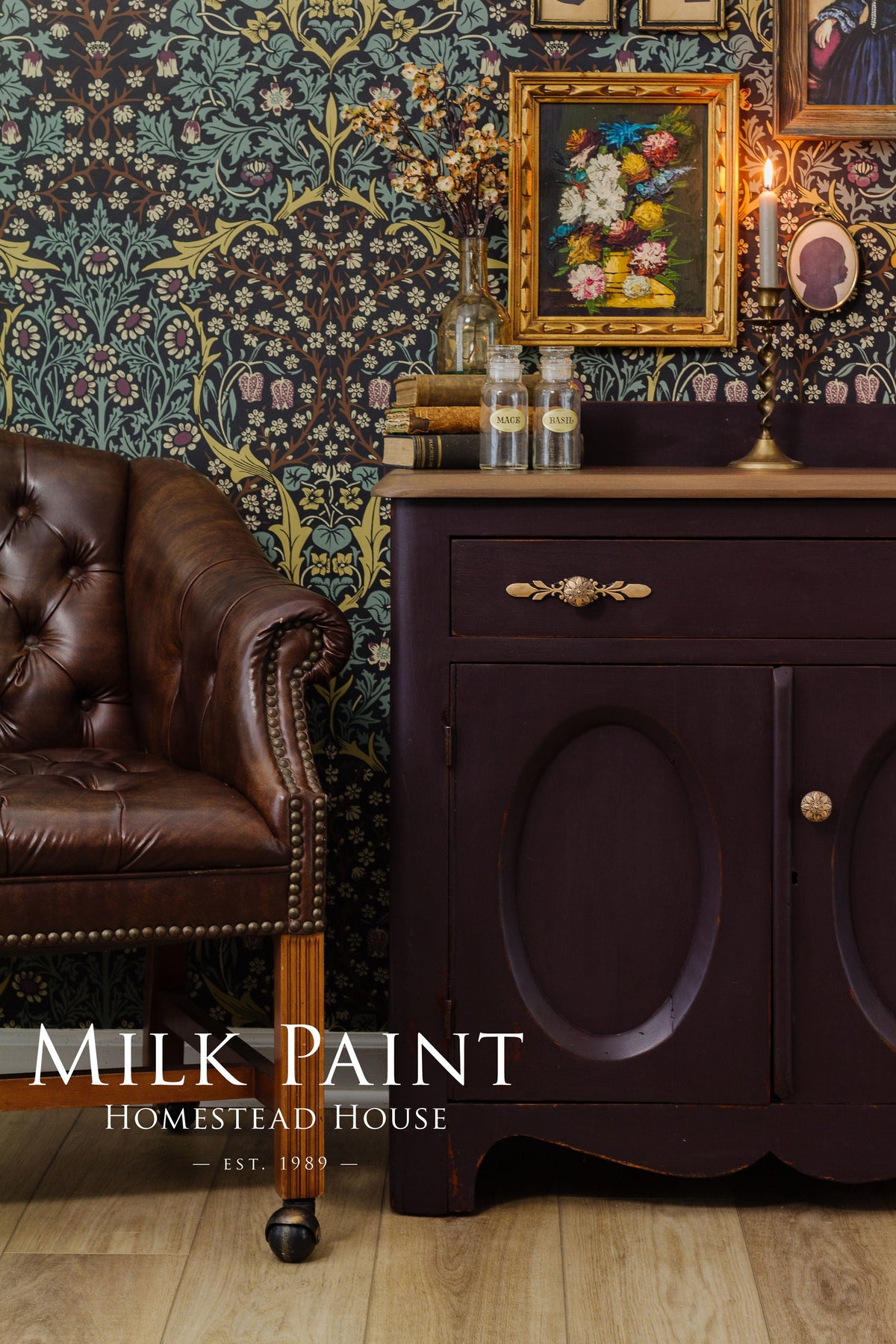 Homestead House Mennonite Red Milk Paint cabinet with brown leather chair, floral wallpaper, and art in background.
