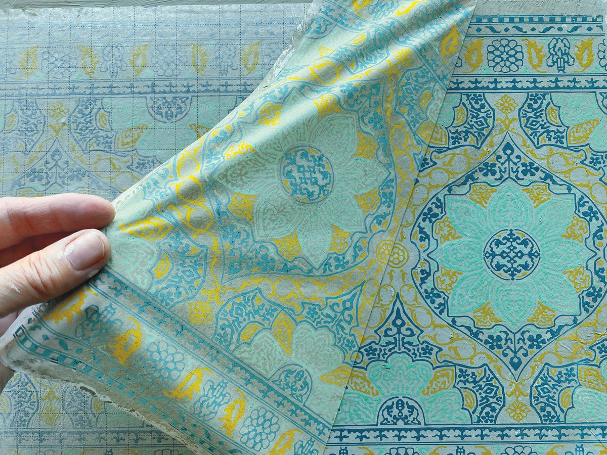 Hand lifting I.O.D. Morocco Paint Inlay fabric with teal, yellow, and blue designs over a coordinated background.