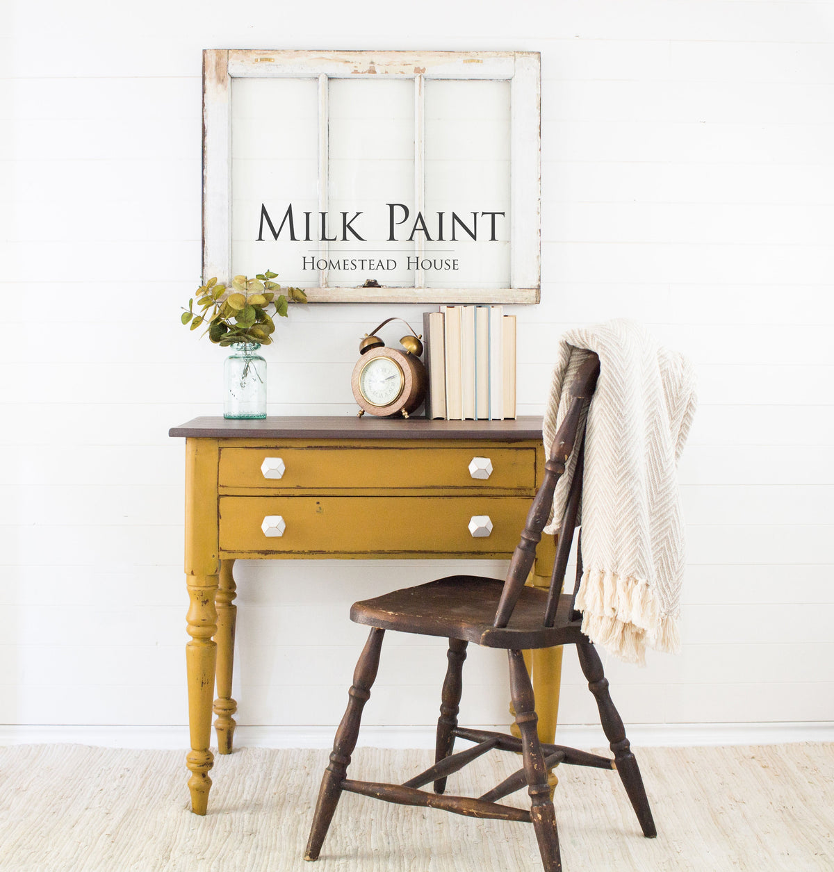 Wooden chair and desk in Homestead House Mustard Milk Paint with books, clock, plant, and a blanket on the desk.