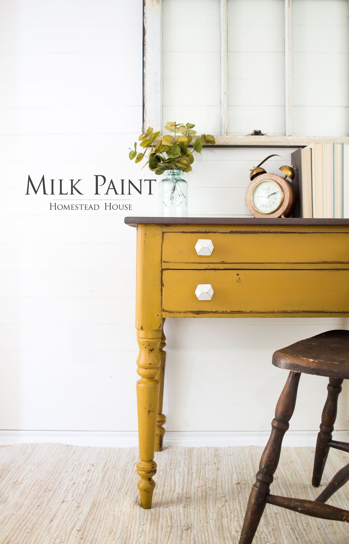 Yellow desk in Mustard Milk Paint by Homestead House with white knobs, shown with plant, clock, and books.