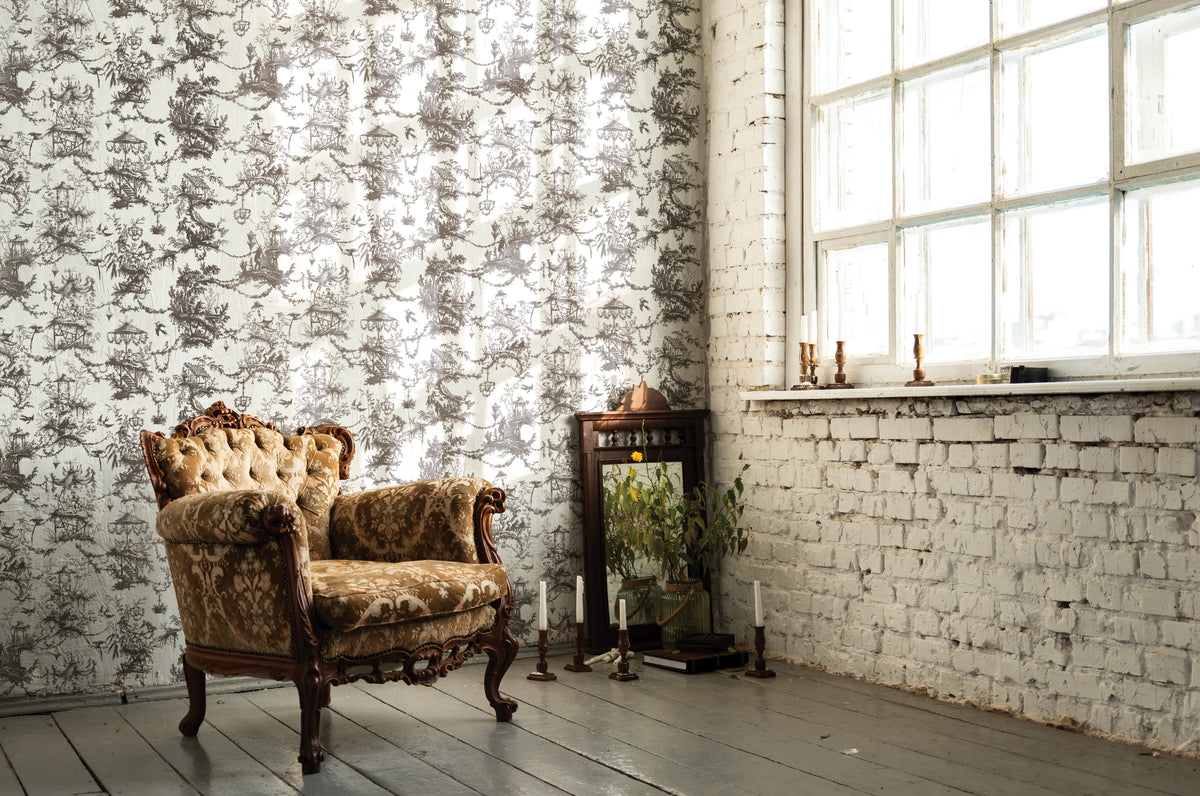 Ornate armchair on wood floor featuring Petits Parasols Black Paint Inlay by IOD, with candles nearby.