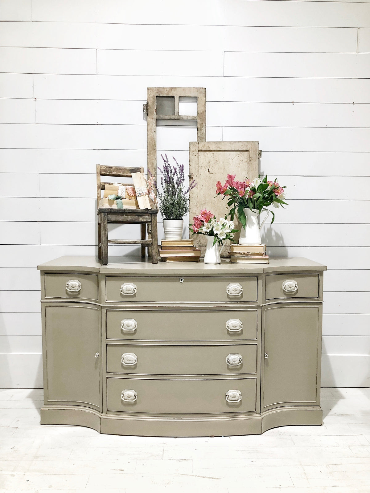 Beige dresser painted with Proper by Sweet Pickins Milk Paint, white handles, topped with flowers and books.