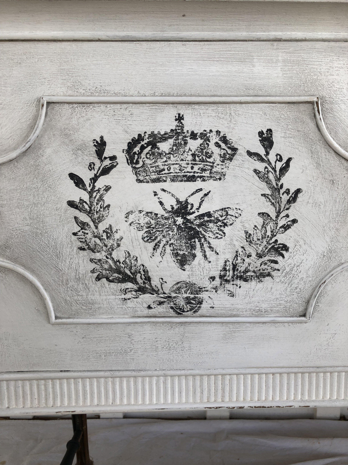 Black crown, laurel, and bee design from Queen Bee Stamp by IOD on distressed white wood background.