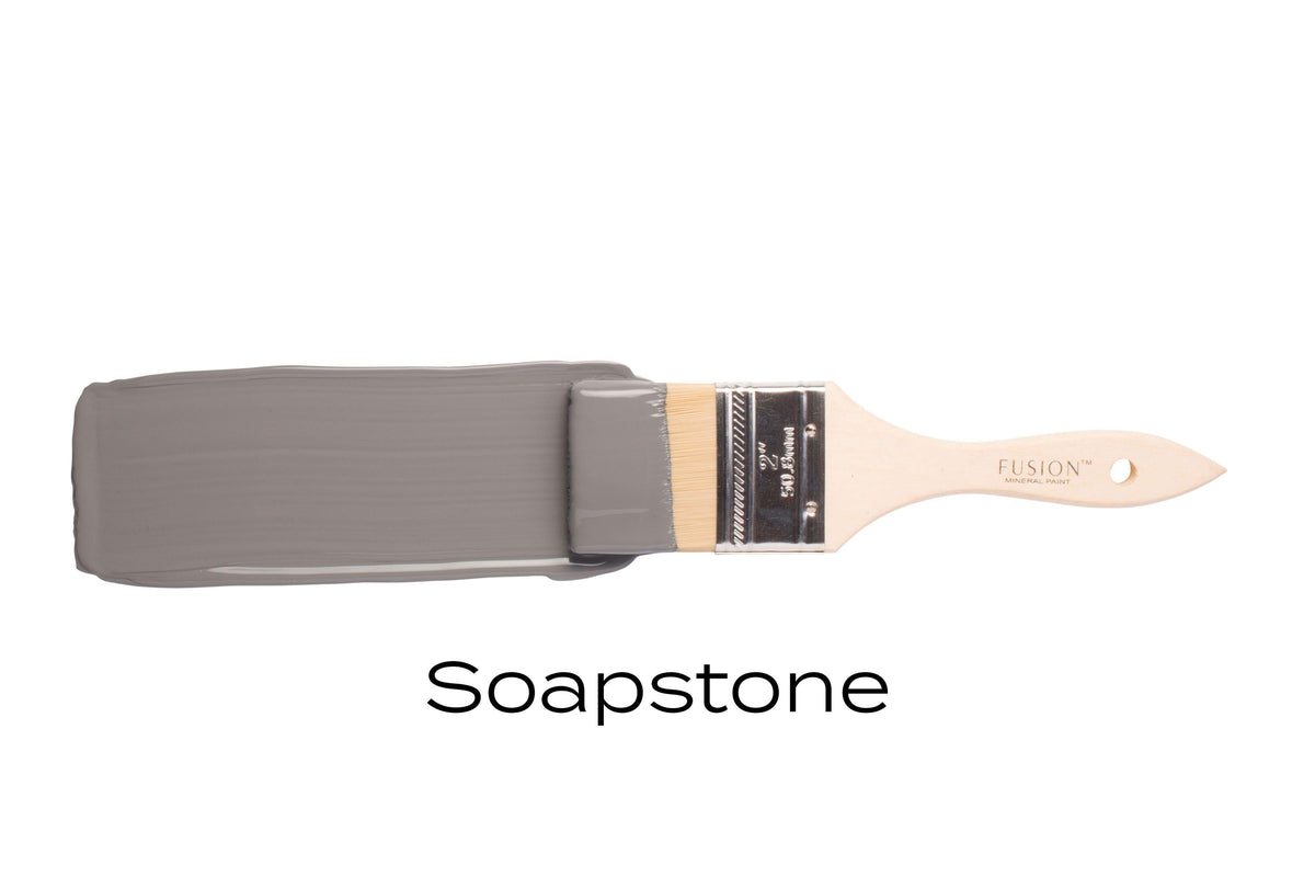 Paintbrush with Fusion Mineral Paint in Soap Stone (deep gray, matte) by Fusion on white background.