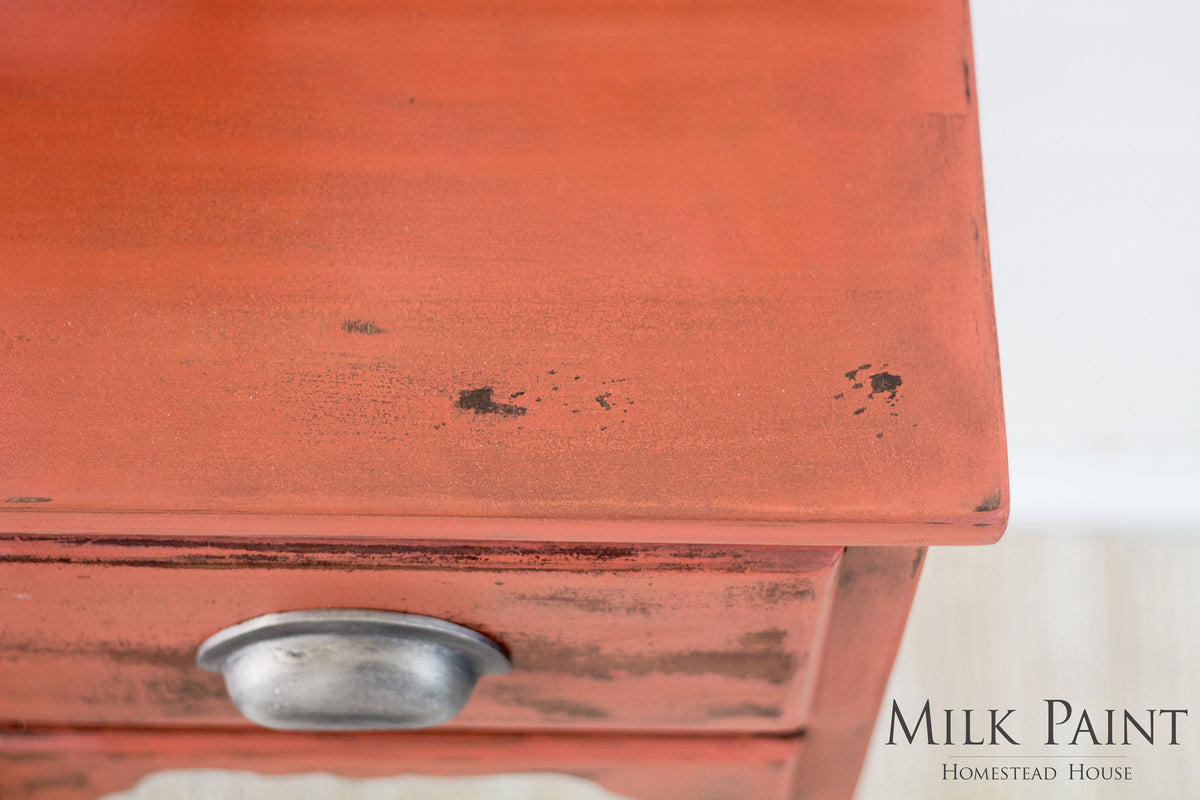 Distressed red drawer with silver knob in Spice Milk Paint by Homestead House; brand text visible in corner.