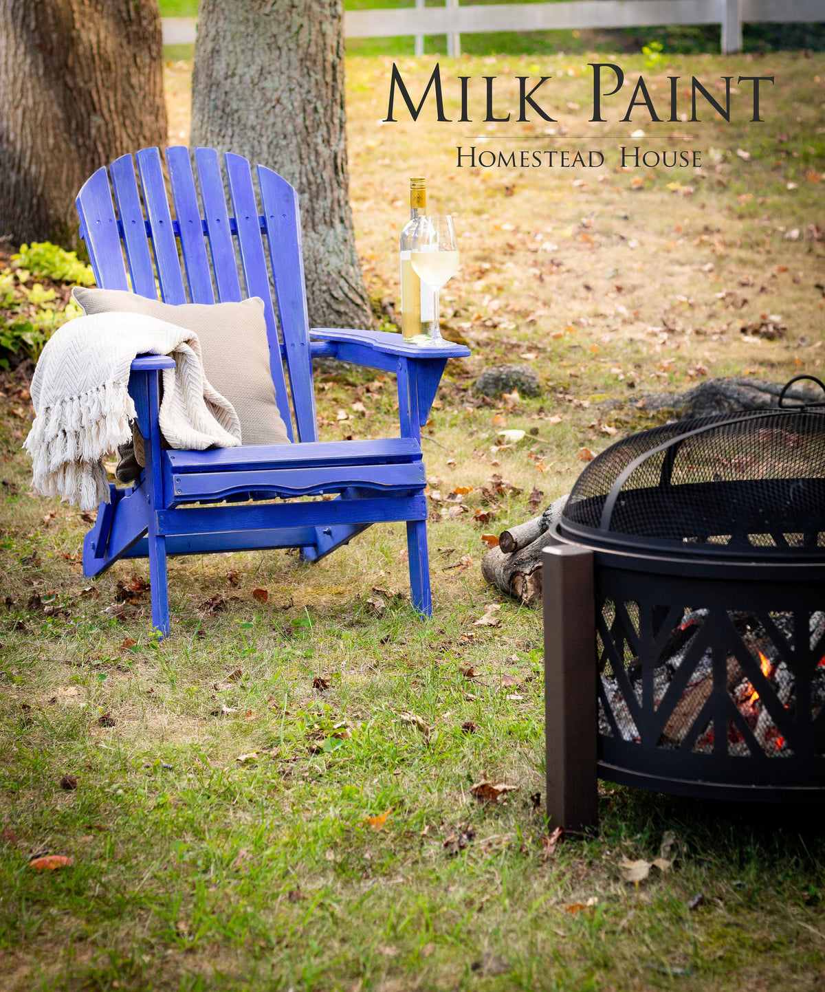 Chair painted St-Laurent Blue Milk Paint by Homestead House, positioned near a fire pit with wine and a pillow nearby.