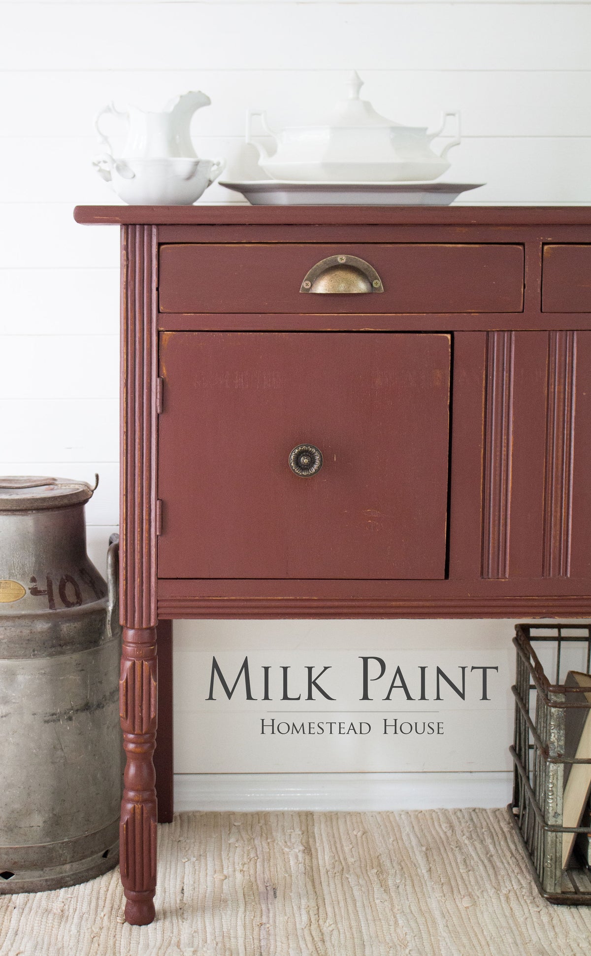 Homestead House Trading Post Red Milk Paint sideboard beside a milk can, topped with white dishes.