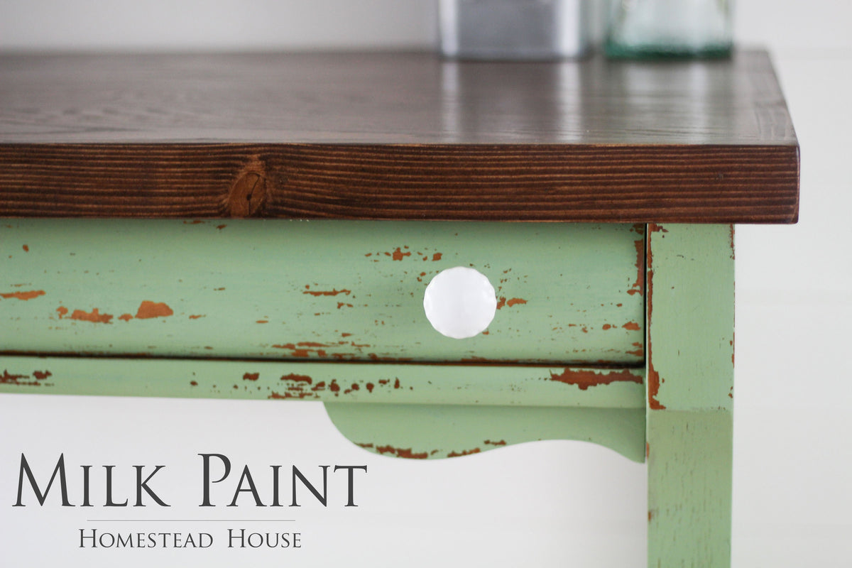 Green distressed wooden table with a dark brown top, finished in Homestead House Upper Canada Green Milk Paint.