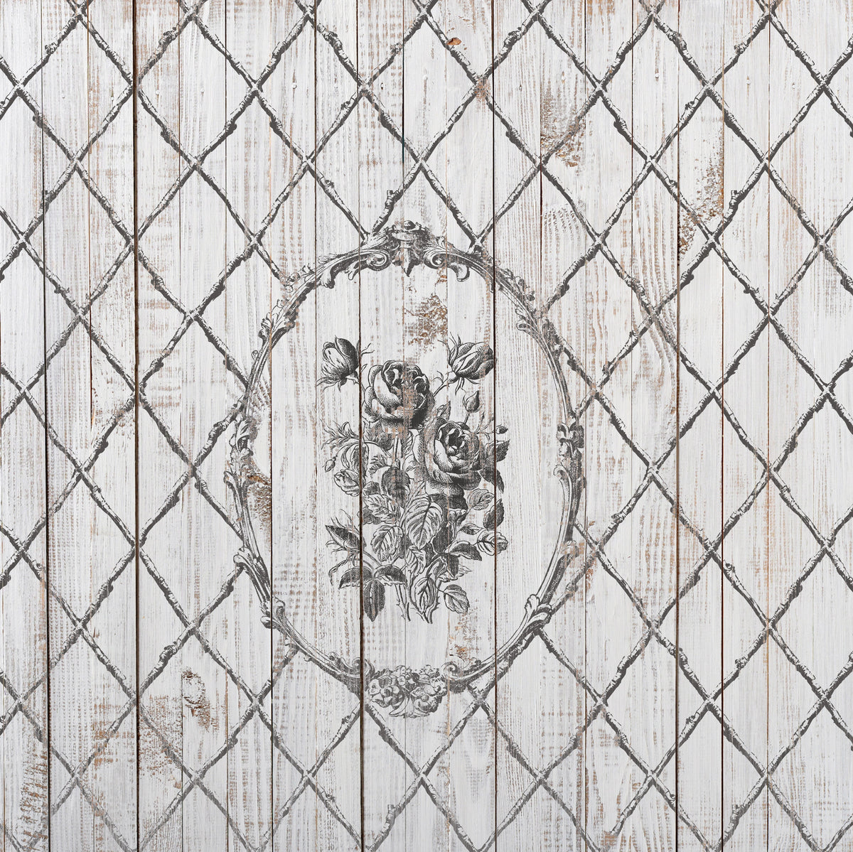 The Veranda Stamp by I.O.D. with a black floral design in an ornate oval over bamboo lattice wooden planks.
