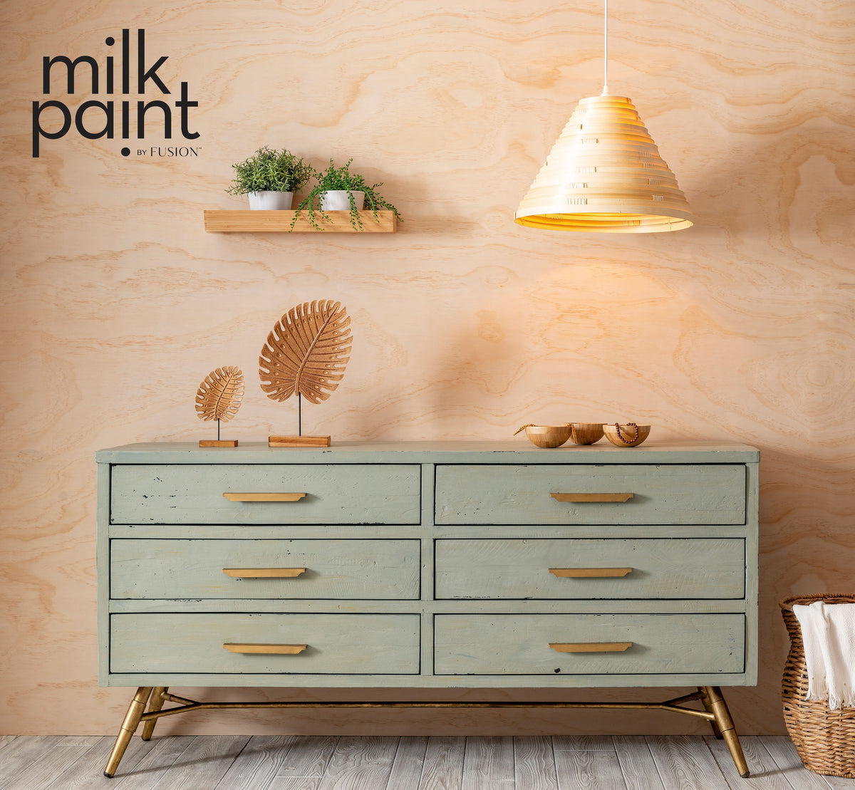 Light green dresser painted in Fusion Mineral Paint Vintage Laurel positioned beneath a wall shelf and lamp.
