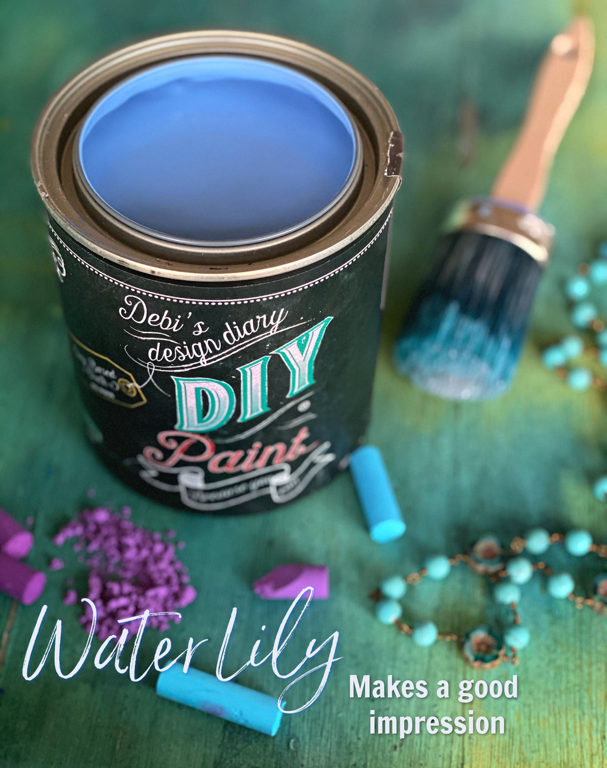 Open can of Water Lily DIY Paint by DIY Paint Co. with brush and turquoise beads on green surface.