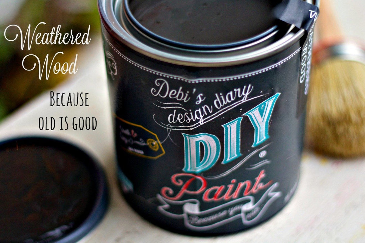 Open can of DIY Paint Co. Weathered Wood paint with lid and paintbrush on table.