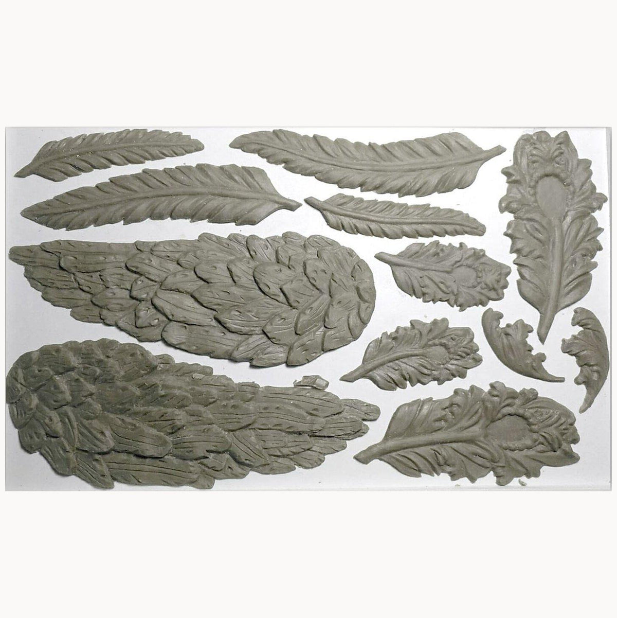 Eleven gray embellishments from the retired IOD Wings and Feathers Mould by I.O.D. displayed on a white surface.