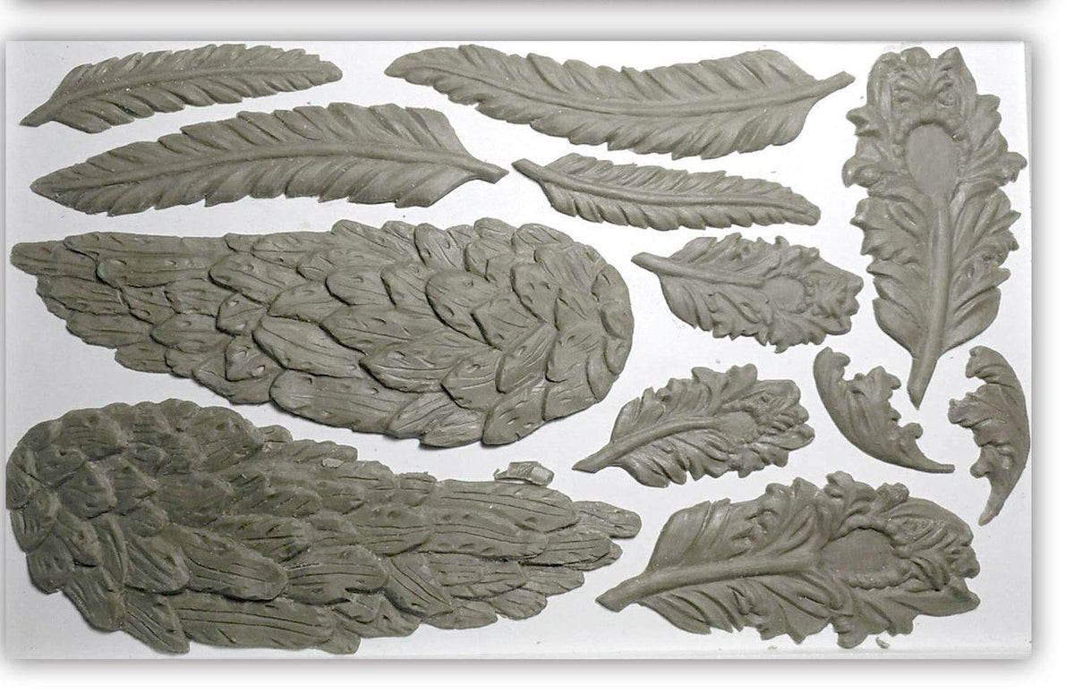 Gray clay feathers and leaves crafted with the I.O.D. Wings and Feathers Mould on white.