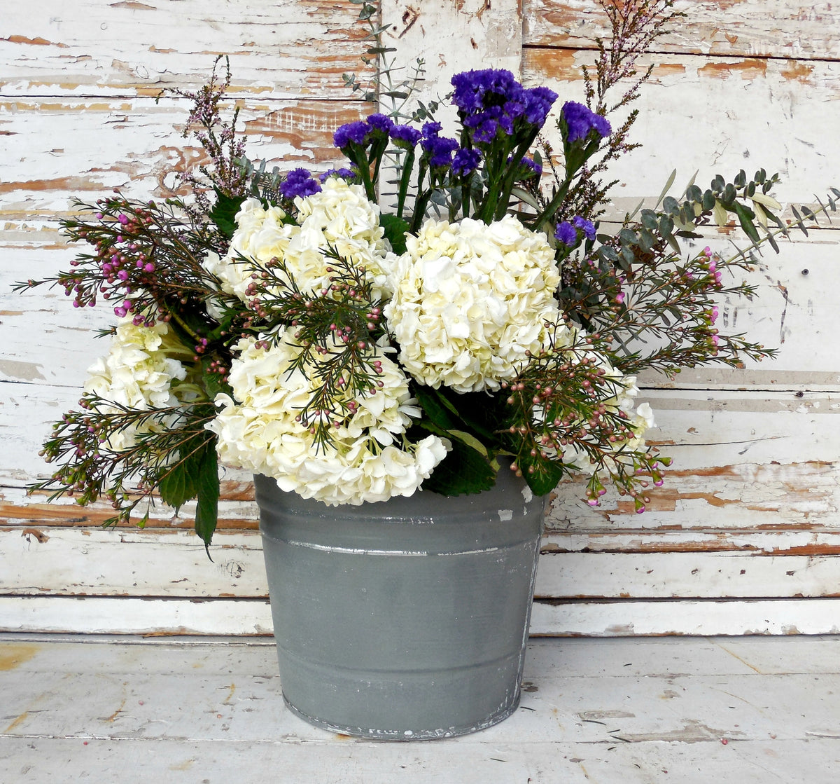 Gray bucket with flowers, shown against wall painted in Old Fashioned Milk Paint’s Zinc – Sweet Pickins shade.