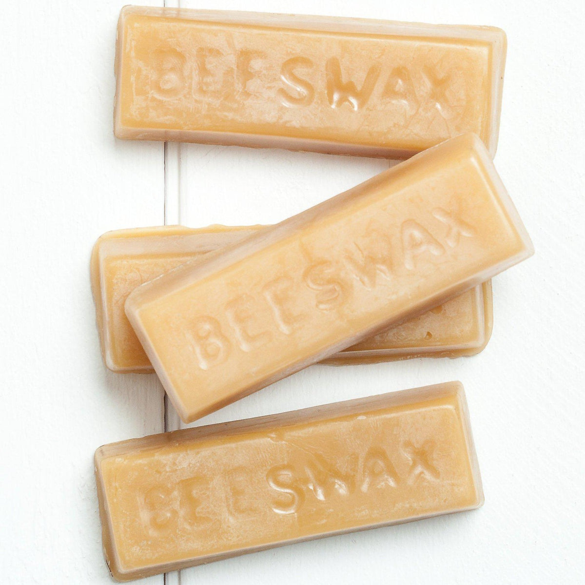 Four Fusion Mineral Paint Beeswax Distressing Blocks, embossed, arranged in a row on a white surface.