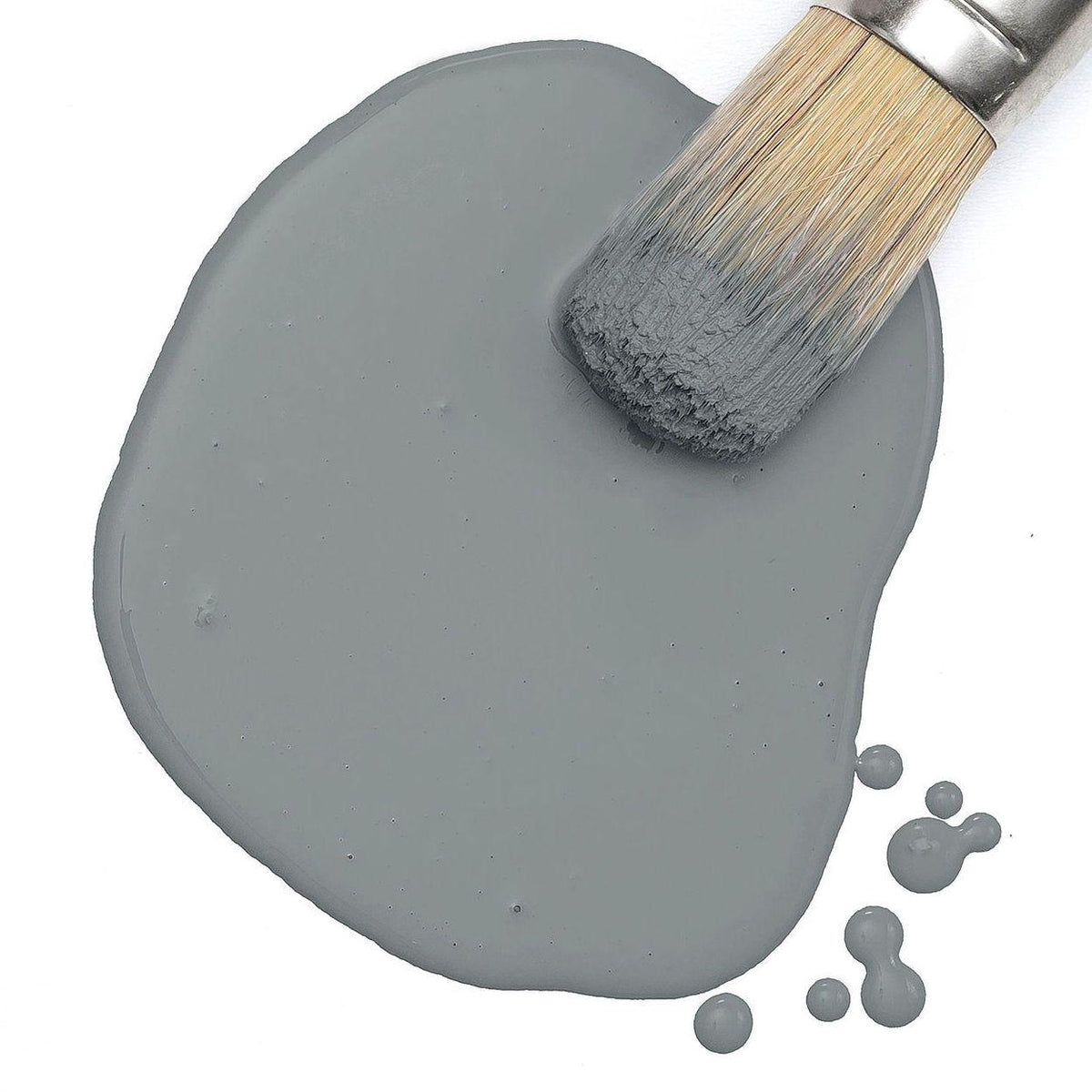 Gotham Grey Milk Paint by Fusion Mineral Paint pooled on white with a paintbrush resting on the surface.