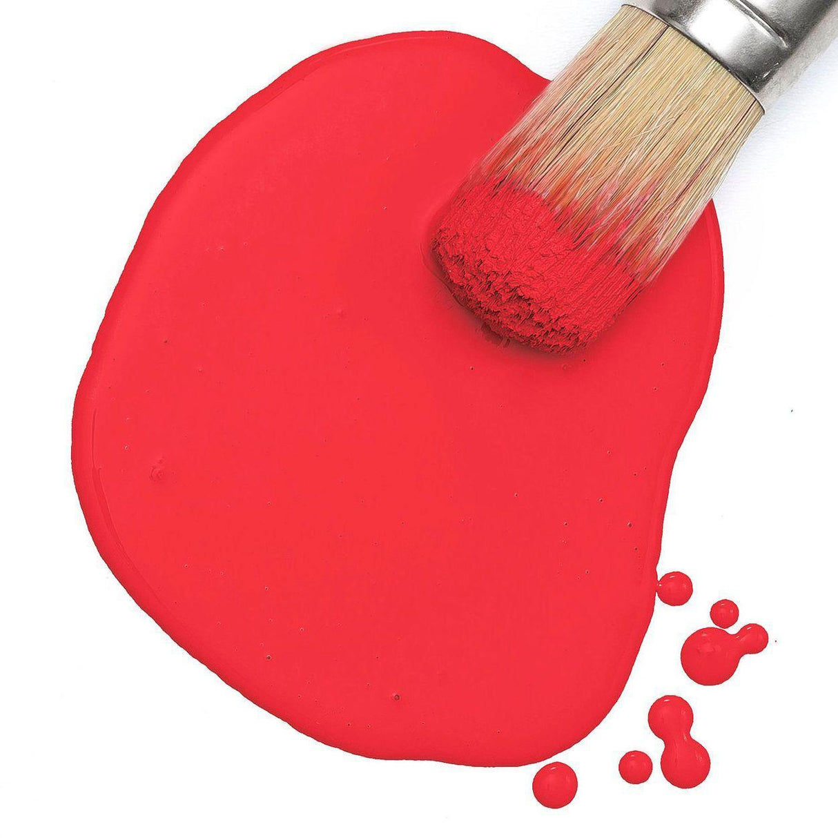 Brush with red bristles on spilled Fusion Hawaiian Hibiscus Milk Paint, surrounded by vibrant droplets.